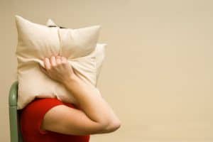woman covering her head with a pillow