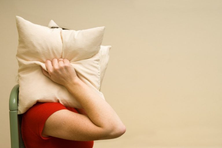 woman covering her head with a pillow